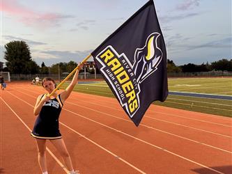 Cheerleader with school flag at a Football game