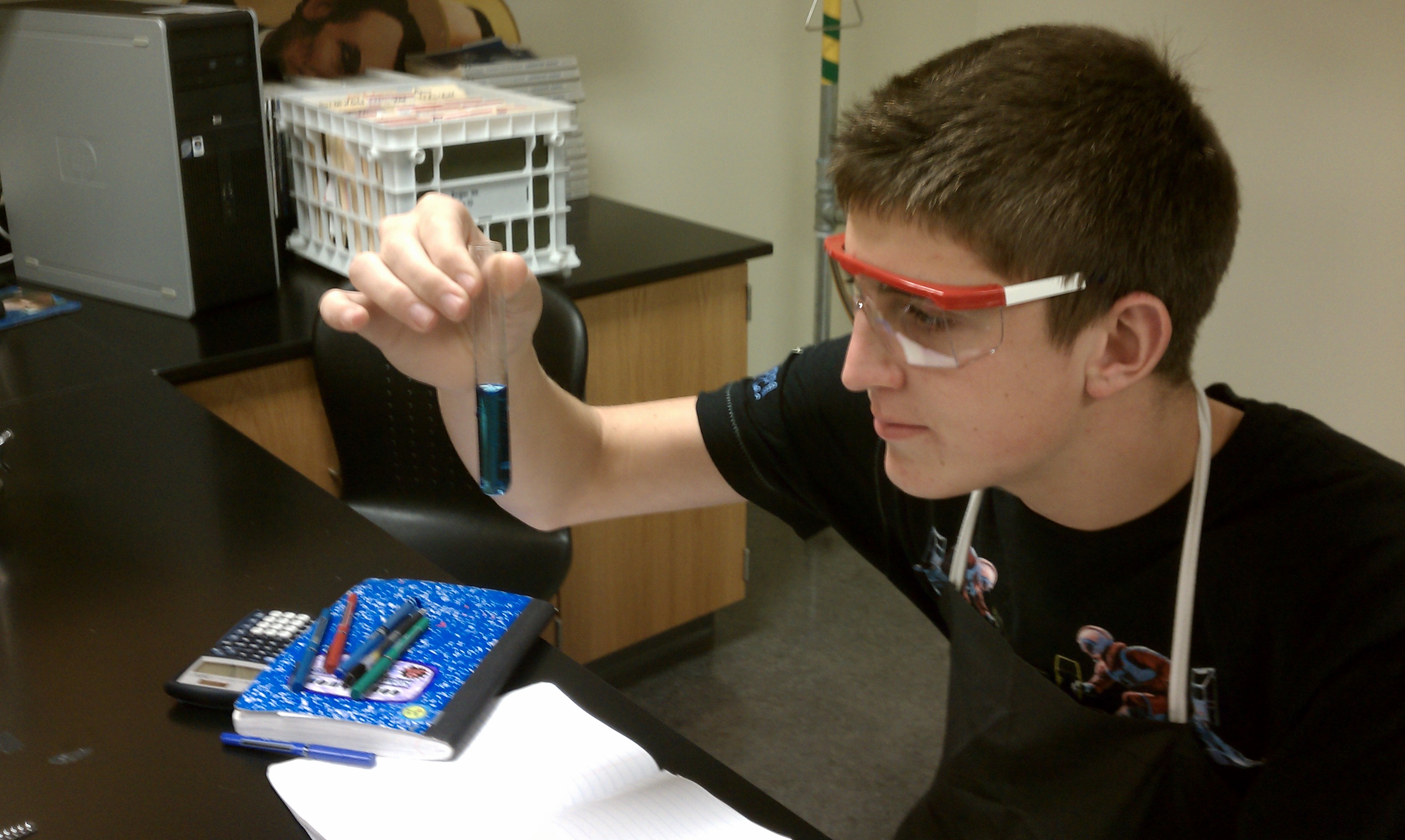 student holding test tube while wearing goggles